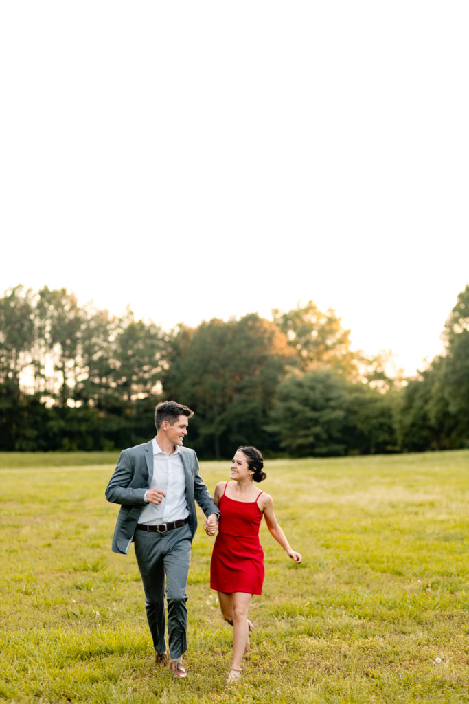couple running through a field in jetton park in charlotte, north carolina