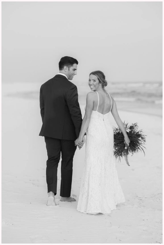 black and white photo of couple walking on the beach at the lodge at gulf state park wedding