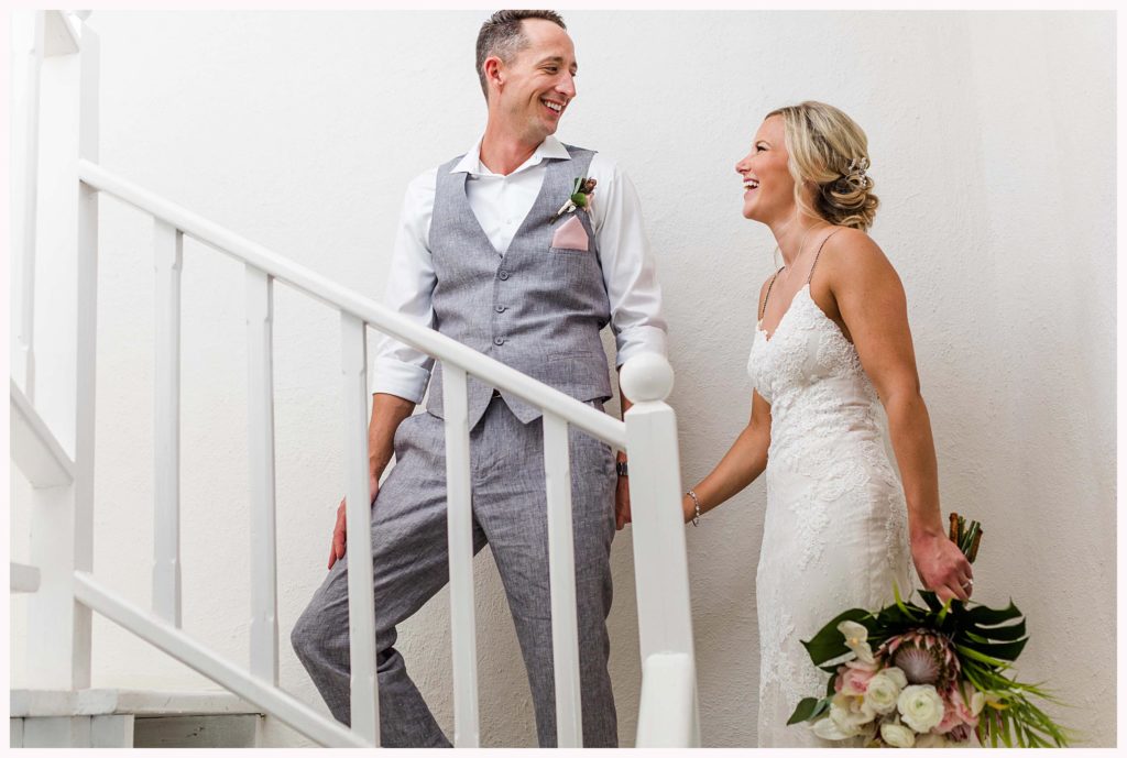 husband leading bride up the stairs in a white room