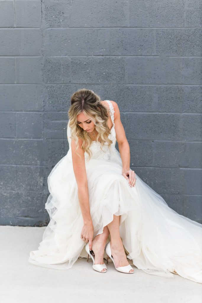 bride putting on her white shoes on wedding day