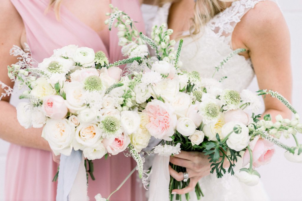 pink, white, and green floral arrangements against bridesmaid in pink dress and bride in white dress
