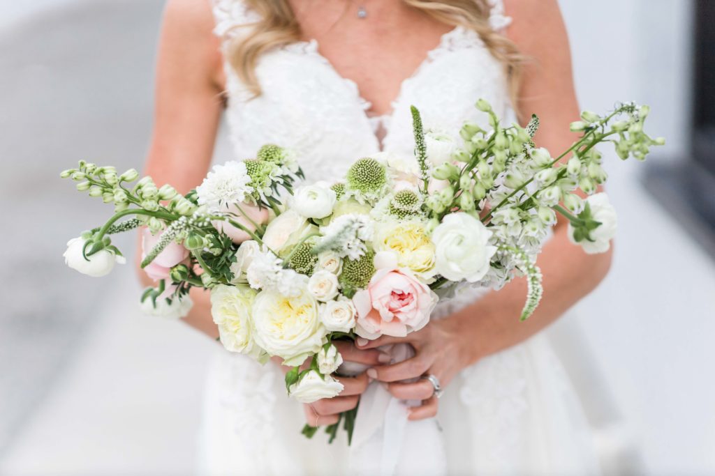hand tied pink, white, and green bouquet against a bride's dress