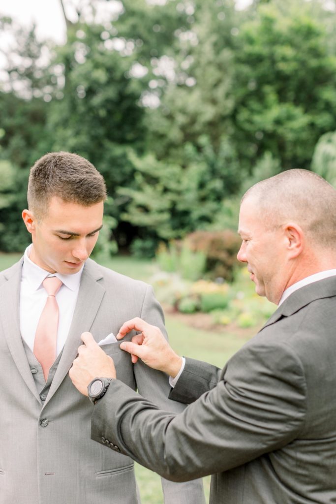 father of groom adjusts groom's pocket square on wedding day