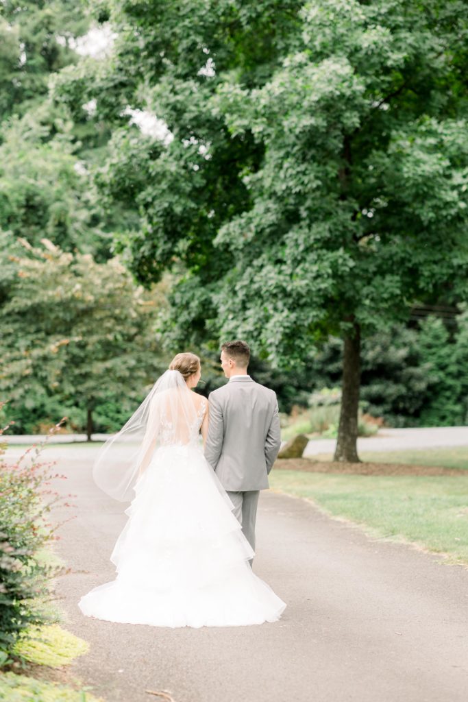 bride and groom walk hand in hand down a cement road in a garden at alexander homestead