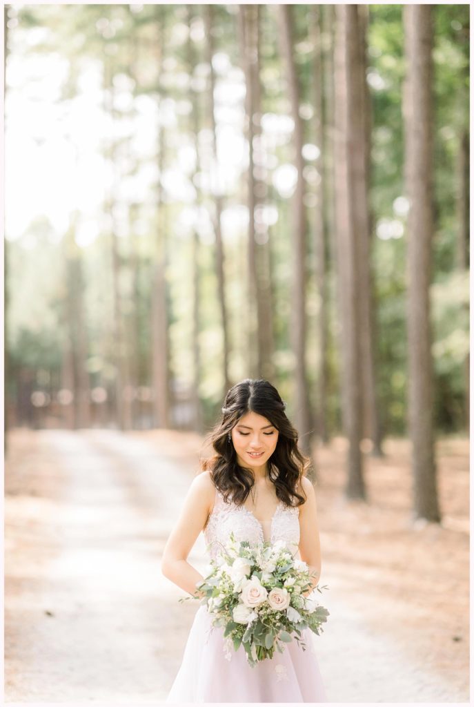 stunning bride looks down at bouquet in the forest