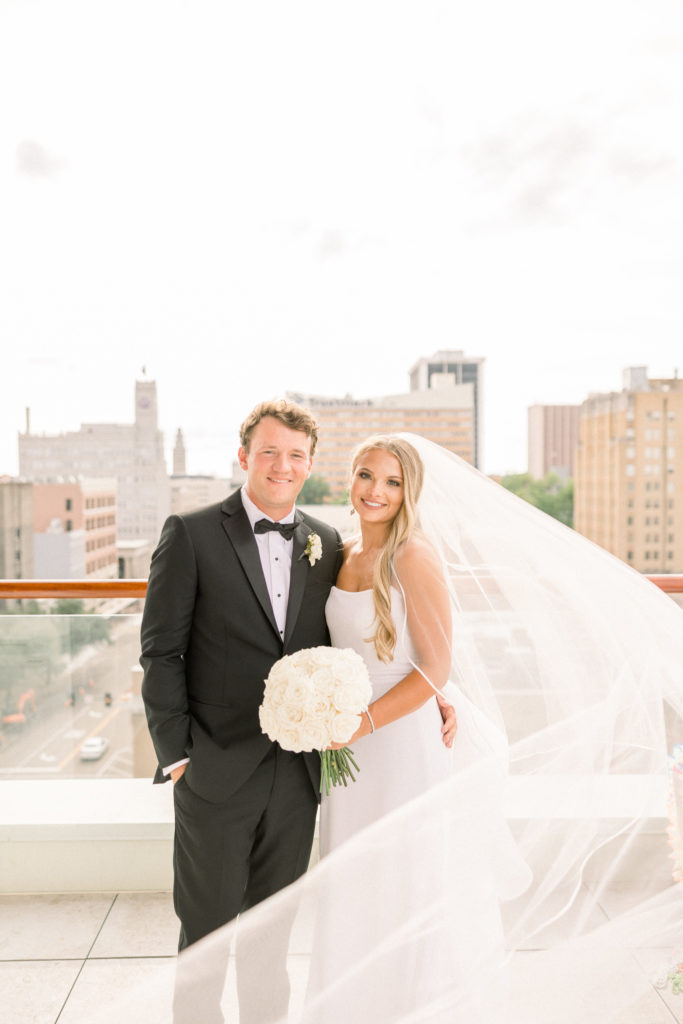 bride and groom smile at camera on the rooftop of the faulkner jackson mississippi wedding venue