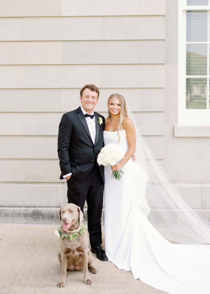 bride and groom pose with their hunting dog on wedding day