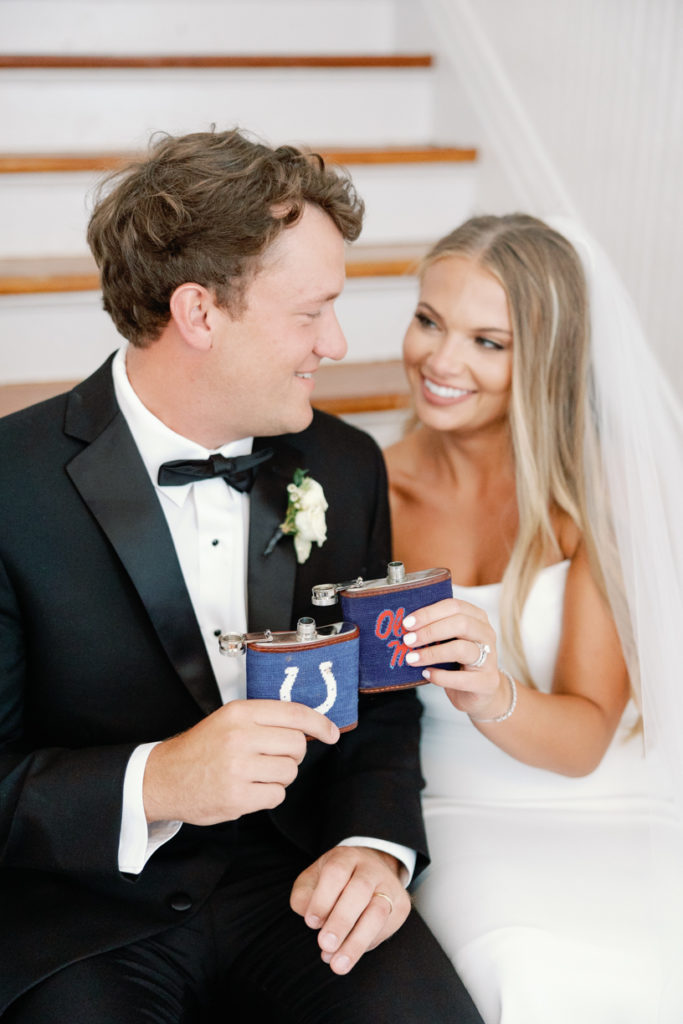 bride and groom cheer with colts and ole miss flask on their wedding day