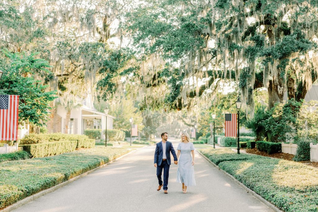 couple wearing blue dress and navy suit walk through the streets of palmetto bluff